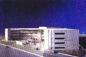 Nighttime view of a modern illuminated building with glass facade and white exterior walls.