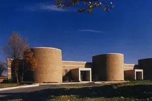 Modern curved brick building with round towers under a clear blue sky