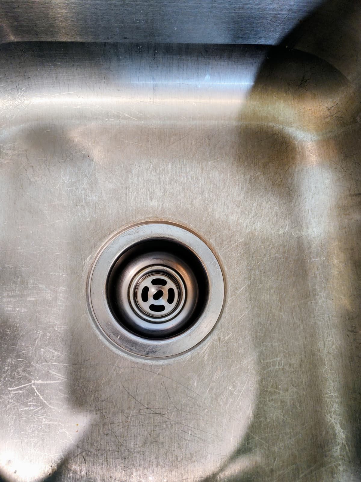 Stainless steel sink basin with a drain centered in the bottom.