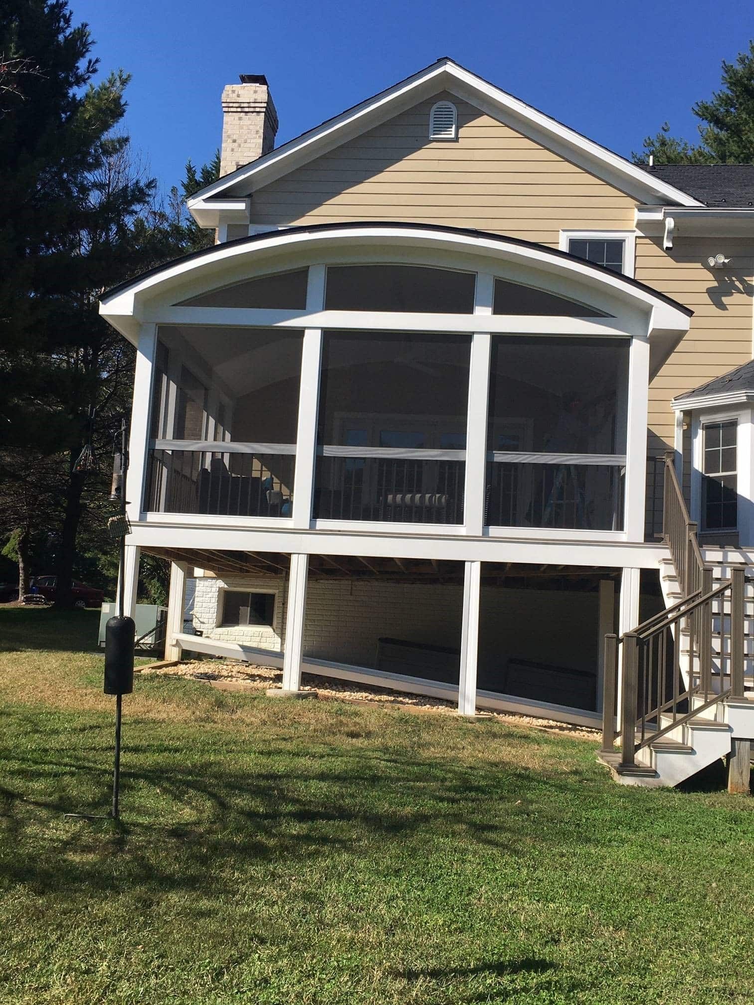 House with a white screened porch and beige siding on a sunny lawn
