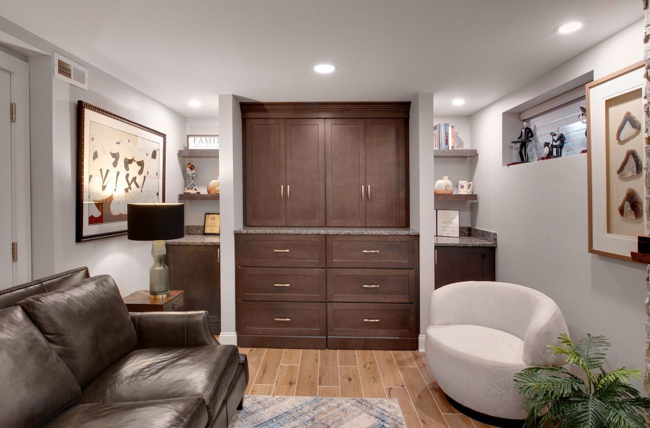 Modern living room with brown sofa, white chair, wood cabinet, and framed wall art