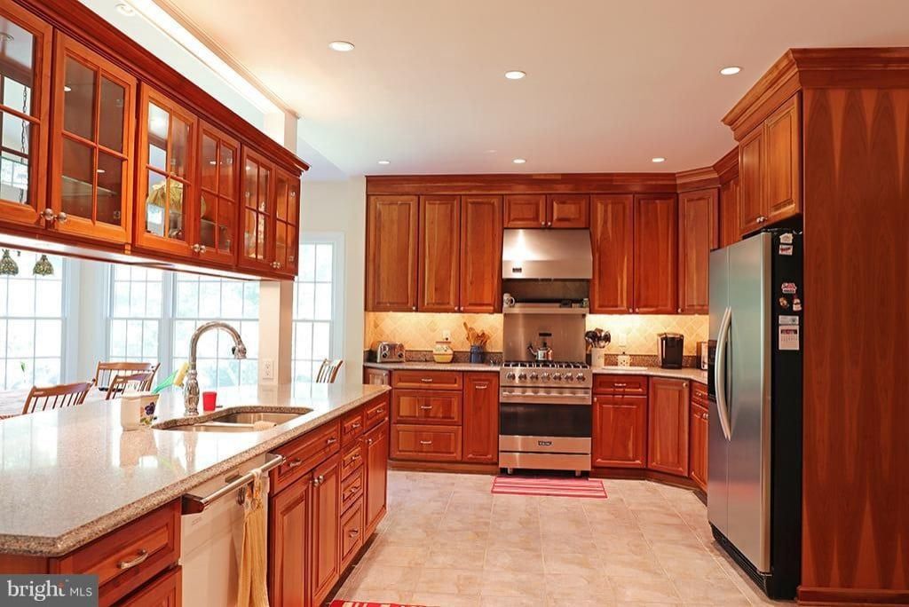 Bright kitchen with cherry wood cabinets, stainless steel appliances, and a large window over the sink.
