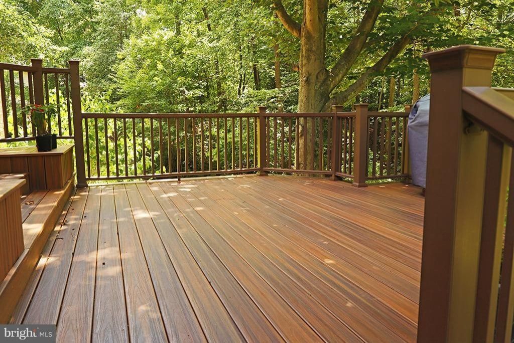 Wooden deck with railing overlooking a lush green wooded area