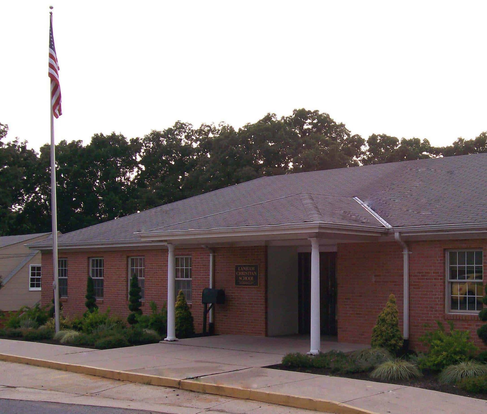 Single-story brick building with an American flag and front entrance, seen from the street.