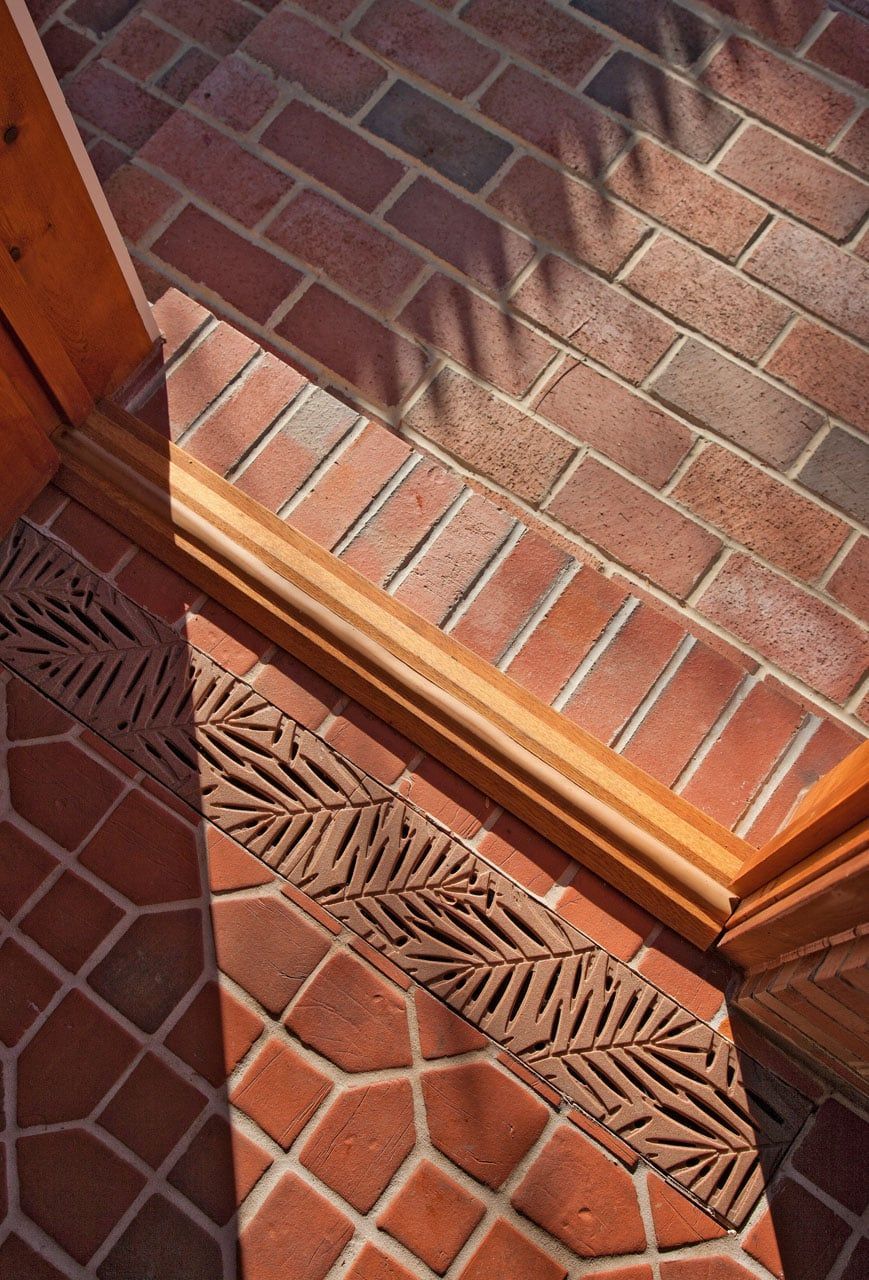 Sunlit brick step and terracotta tile floor with a carved wooden threshold