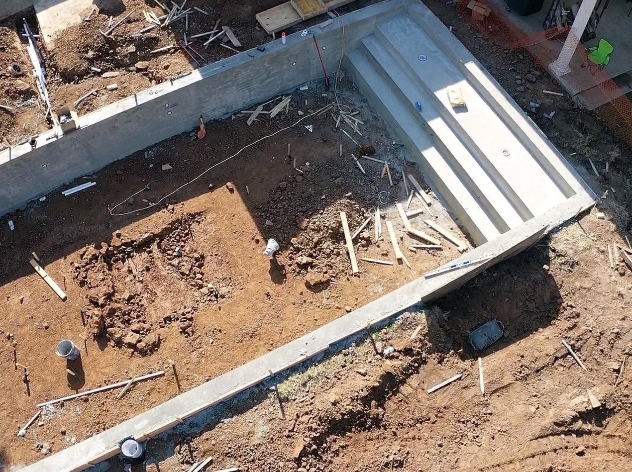 Concrete foundation with dirt fill and a white stairwell structure under construction outdoors