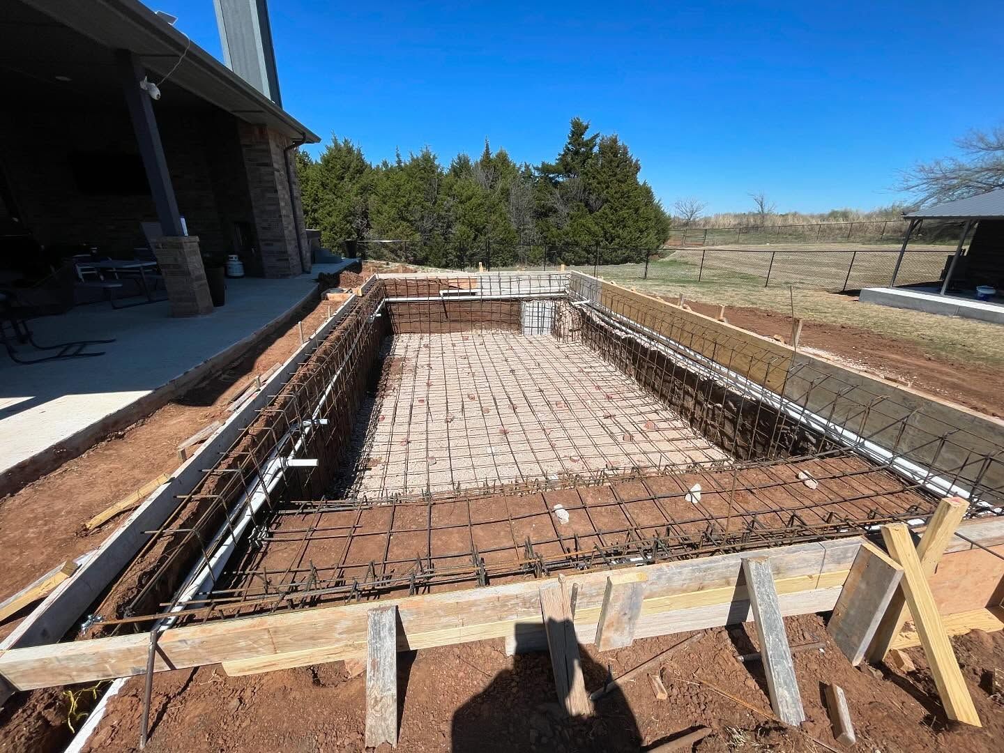 Formwork and rebar for a rectangular concrete slab beside a house under construction