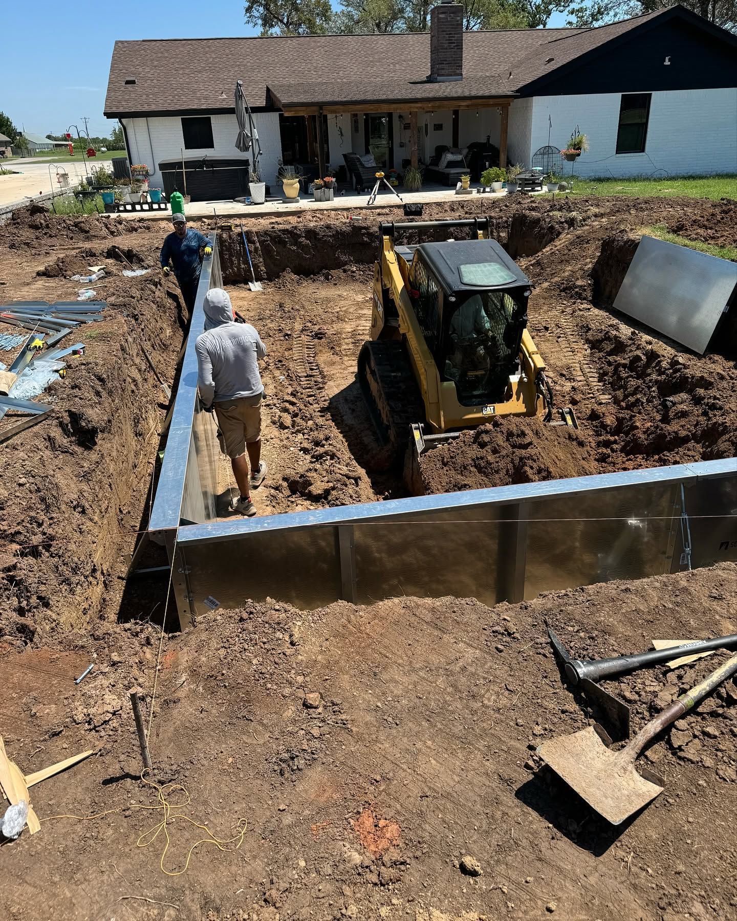 Construction site with a backhoe excavating a foundation beside a stone house