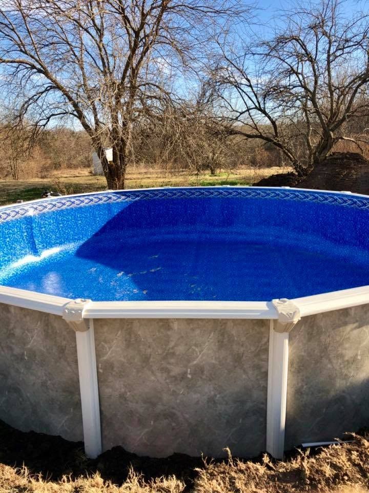 Above-ground pool with bright blue liner in a leafless yard under a clear sky