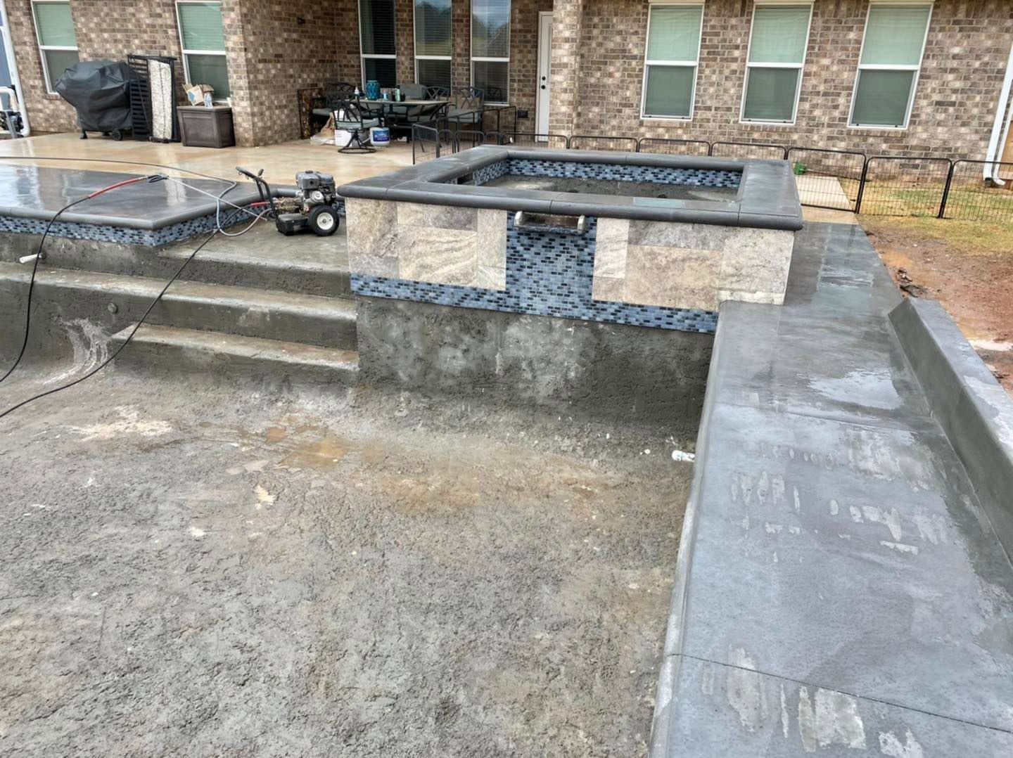 Concrete steps and ramp beside a brick building, with a small cart and stone benches.