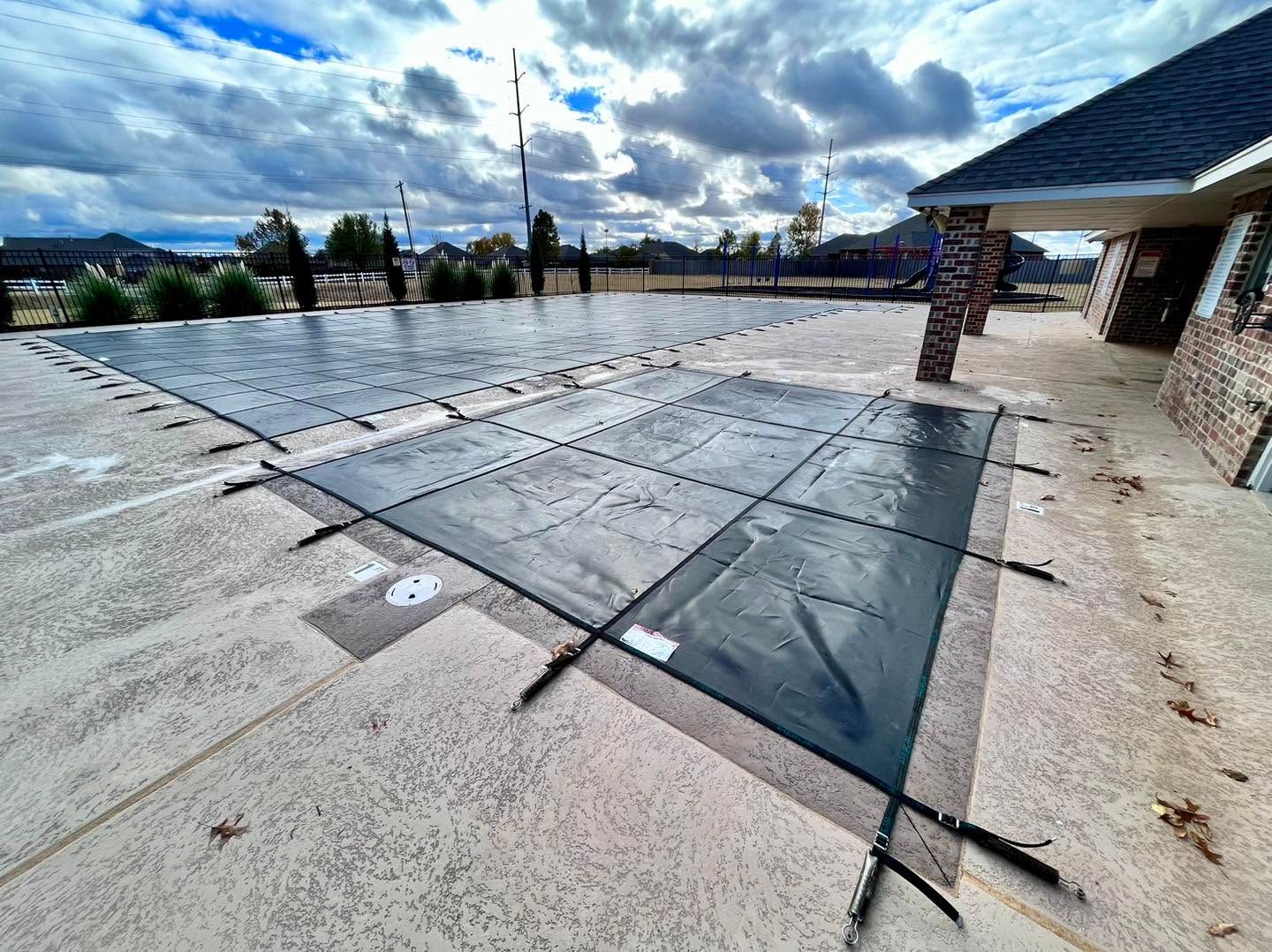 Rooftop with large gray solar panel array under a cloudy sky beside a brick building