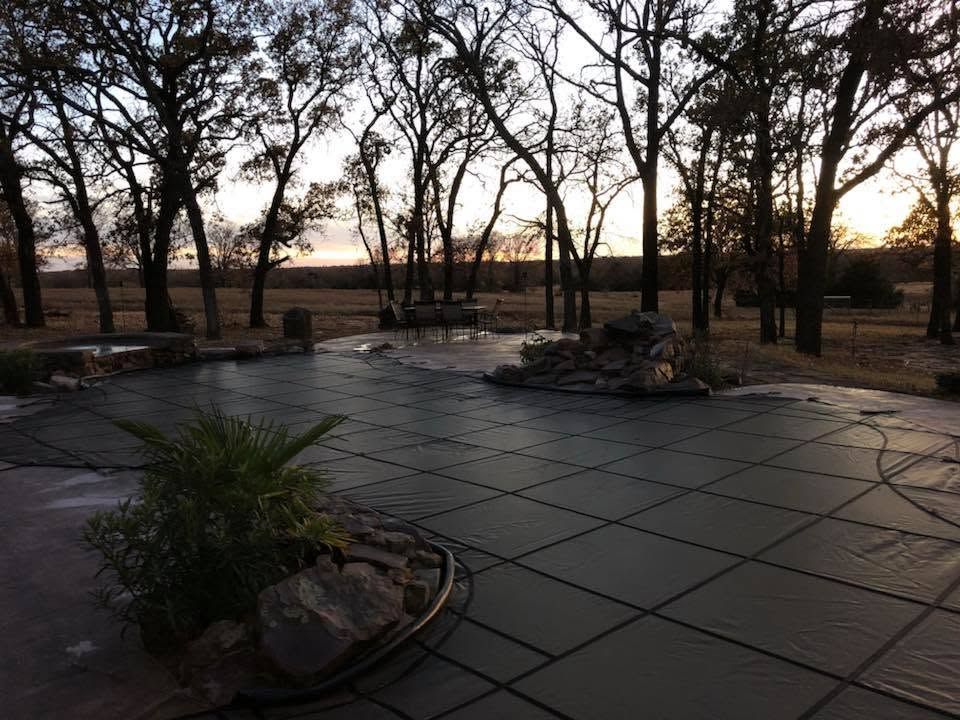 Empty stone patio with planters and bare trees at dusk, overlooking a distant open field