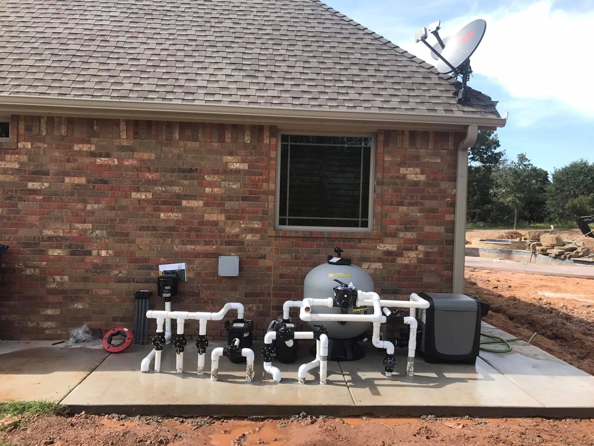 Brick house exterior with an outdoor pool filter and pump system on a concrete slab