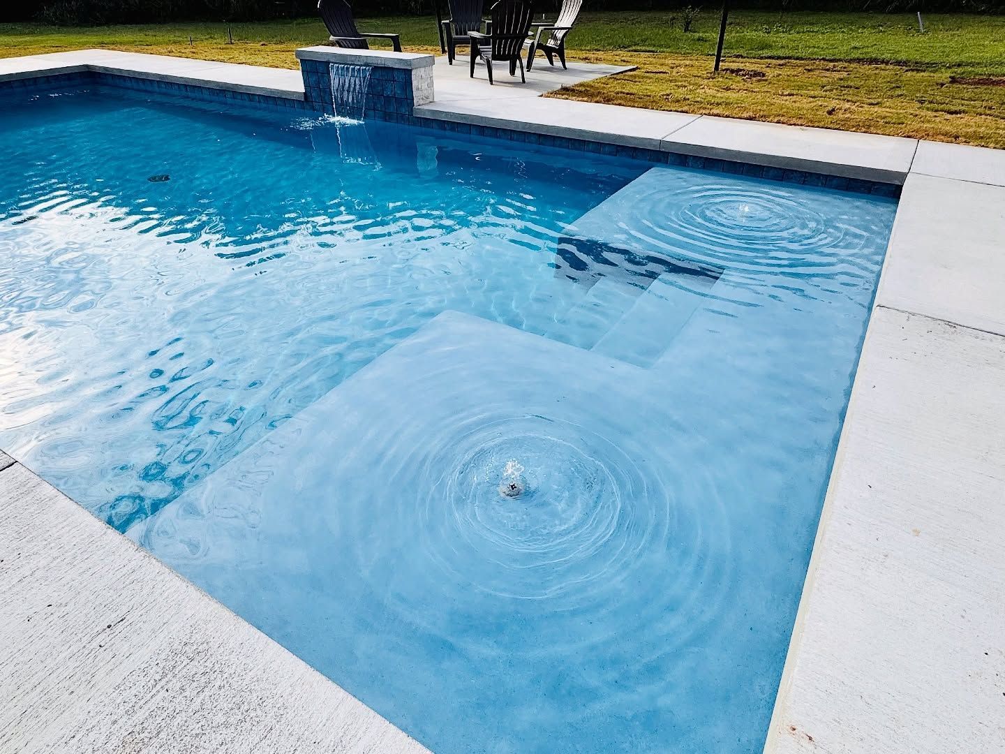 Blue swimming pool with rippling water and a small splash in the center