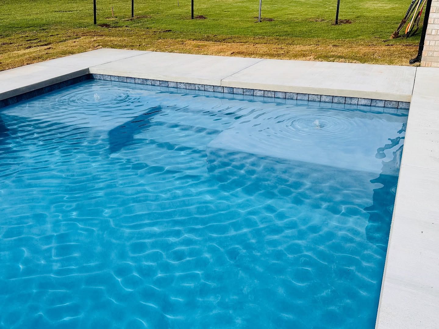 Backyard swimming pool with clear blue water and white coping