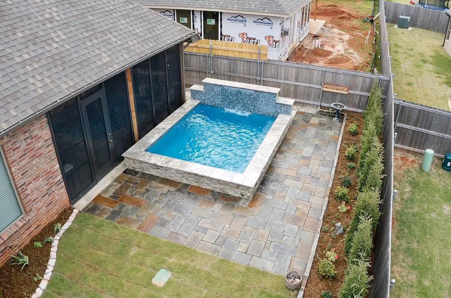 Backyard with a small above-ground pool beside a house and fenced patio area