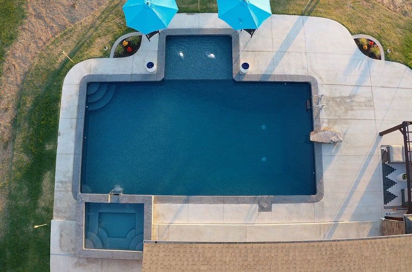 Backyard swimming pool with a small waterfall and patio chairs beside it