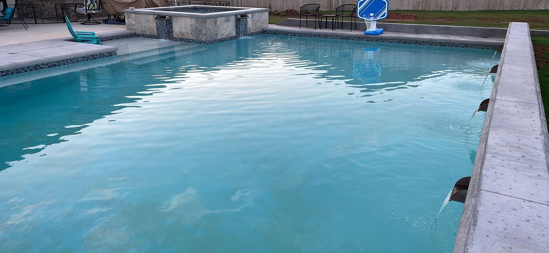 Empty outdoor swimming pool with blue water and concrete deck