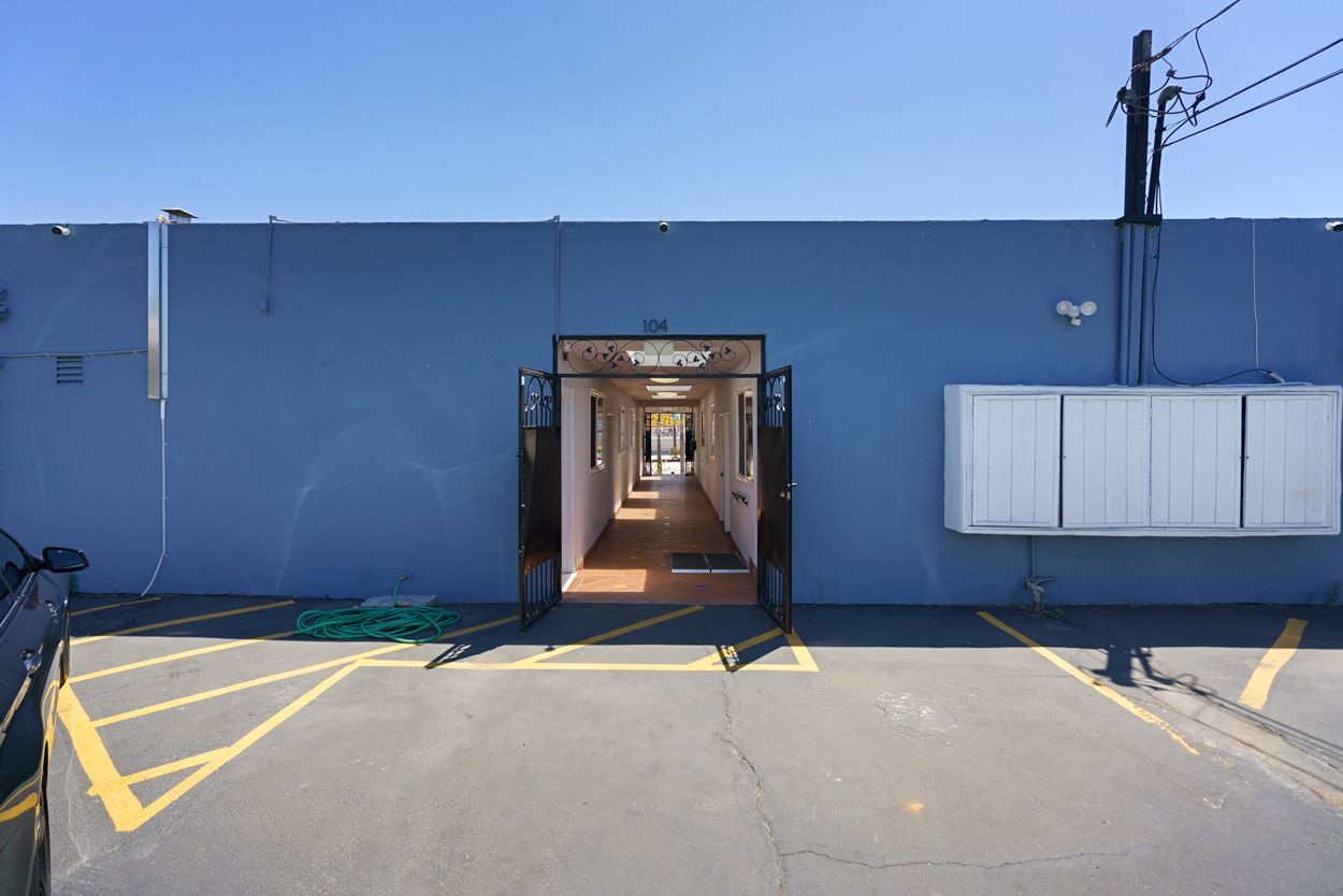 A car is parked in front of a building with a long hallway leading to it.