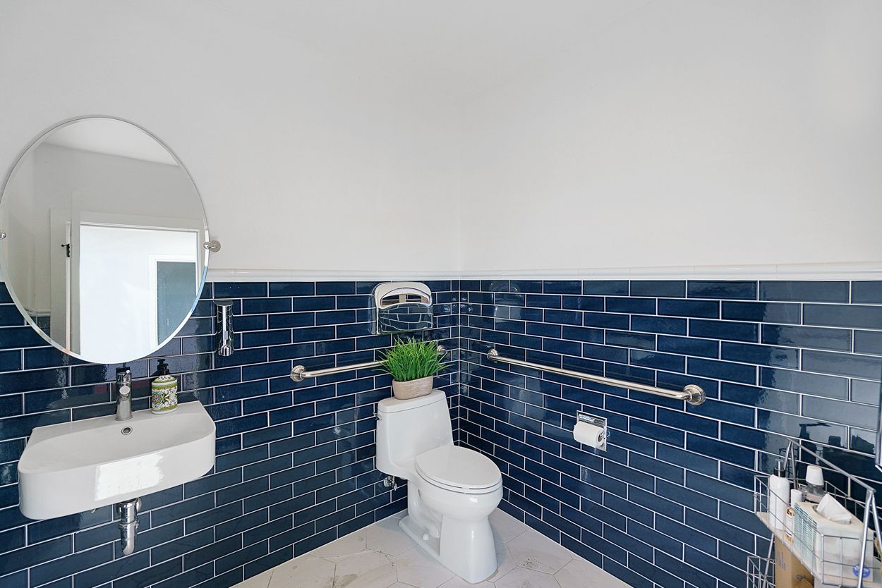 A bathroom with a toilet , sink and mirror.