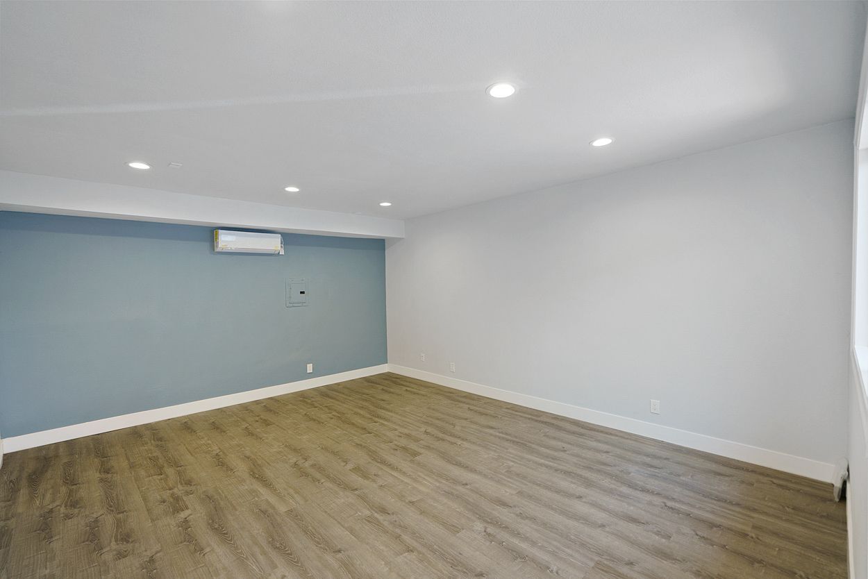 An empty room with hardwood floors and a blue wall.