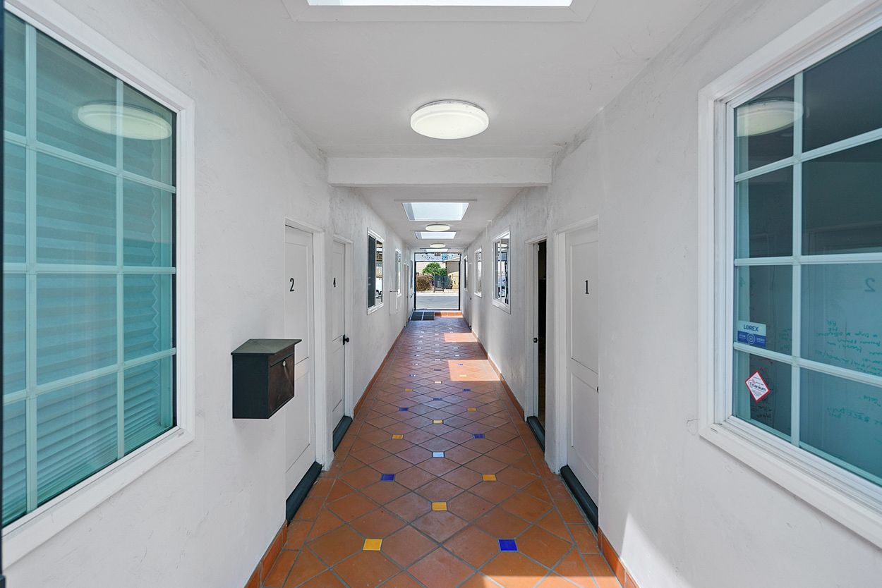 A long hallway with a skylight on the ceiling and a mailbox on the wall.