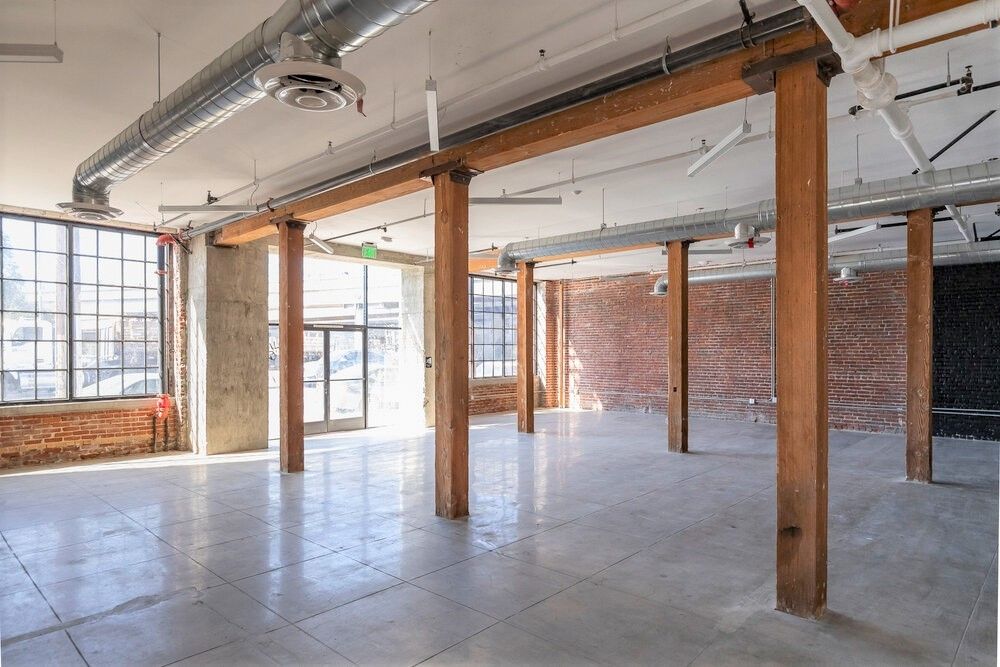 A large empty room with wooden beams and brick walls.