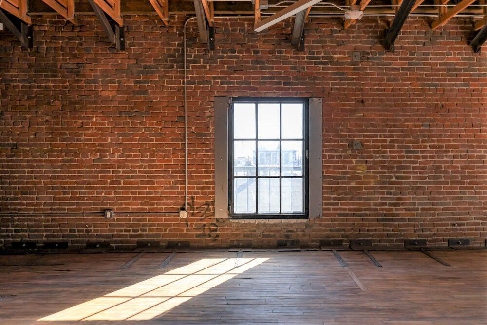 An empty room with a brick wall and a window.