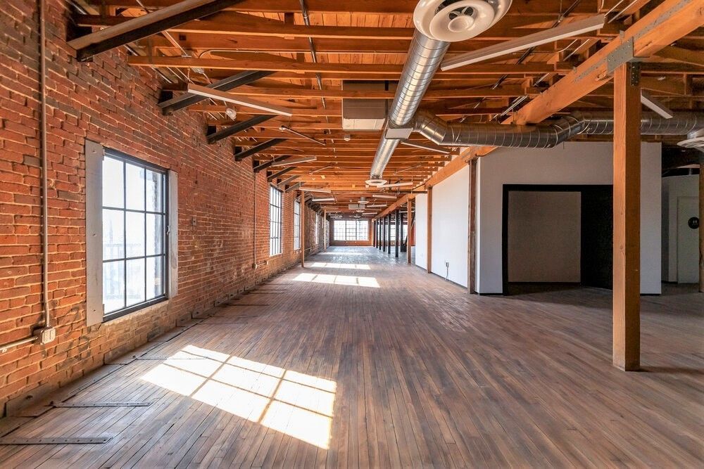 A long empty room with brick walls and wooden floors.