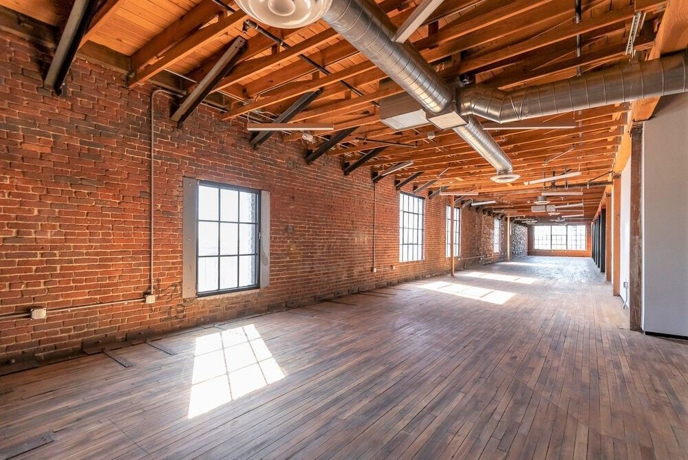 A large empty room with brick walls and wooden floors.