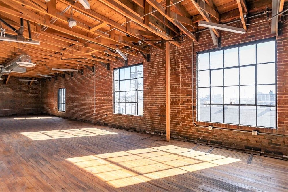 A large empty room with brick walls and wooden floors.