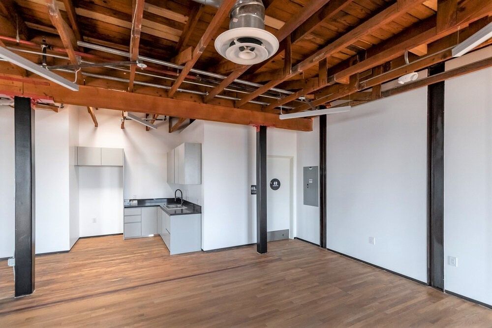 An empty room with wooden beams and a ceiling fan.
