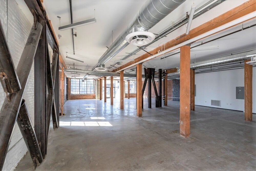 A large empty room with a lot of wooden beams and pipes.