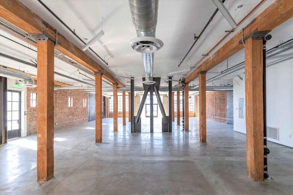 A large empty room with wooden beams and a ceiling fan
