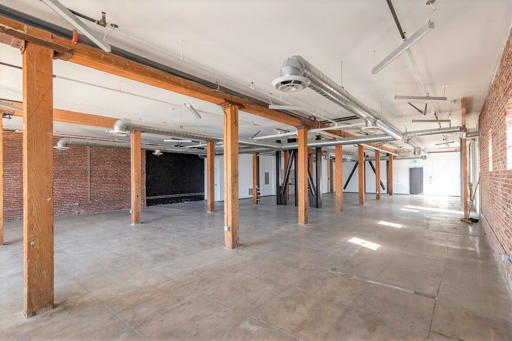 A large empty room with brick walls and wooden beams.
