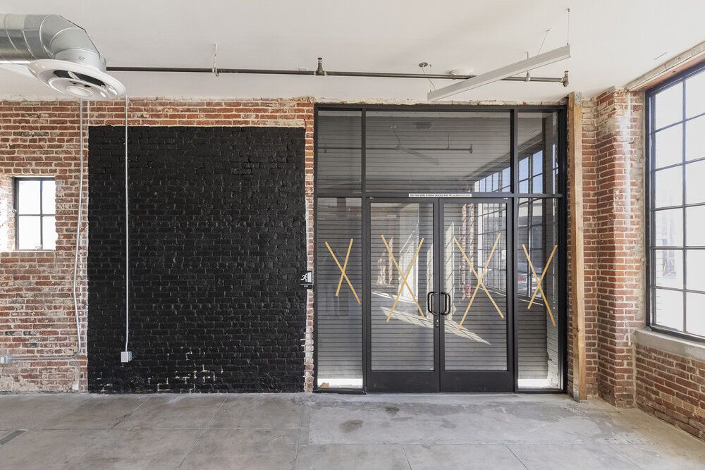 A large empty room with a brick wall and a glass door.
