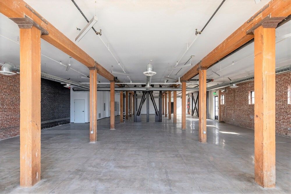 A large empty room with wooden beams and brick walls.