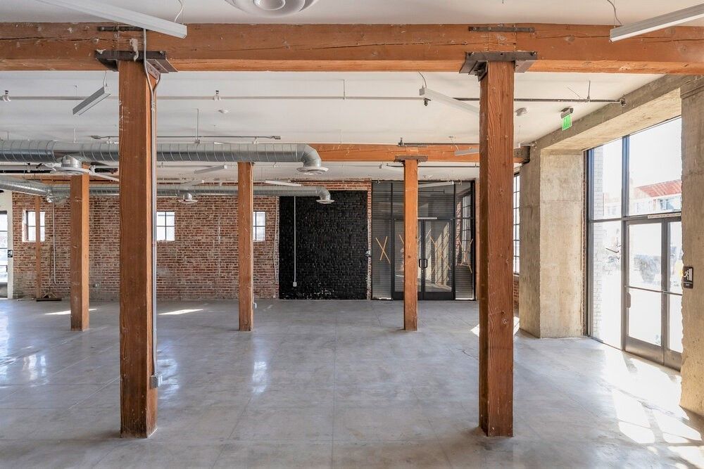 A large empty room with wooden beams and brick walls.