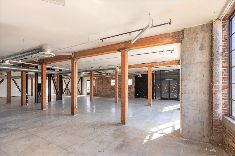 A large empty room with wooden beams and brick walls.