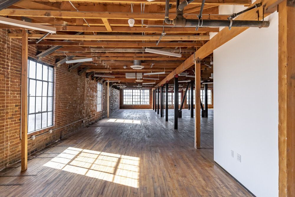 A large empty room with wooden floors and brick walls.