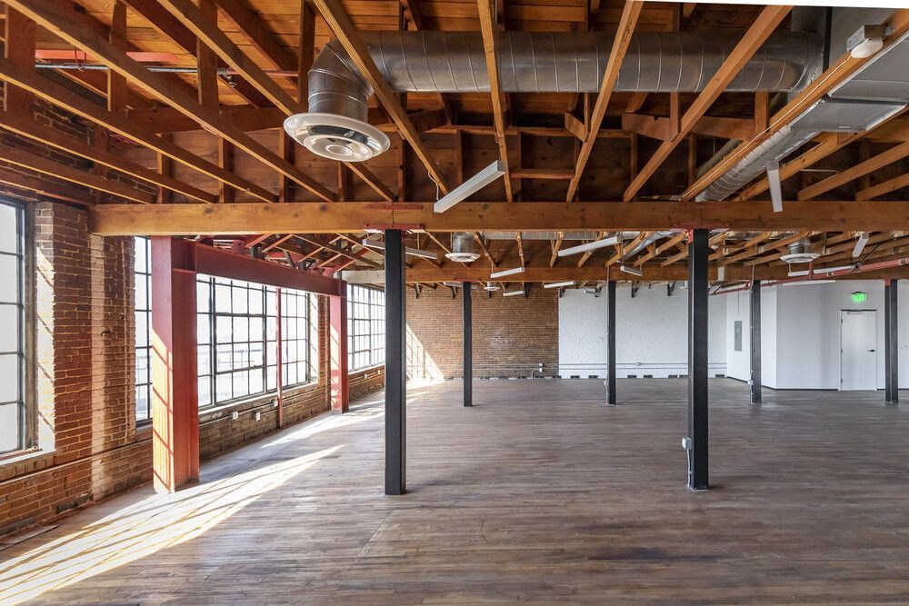 A large empty room with wooden beams and a lot of windows