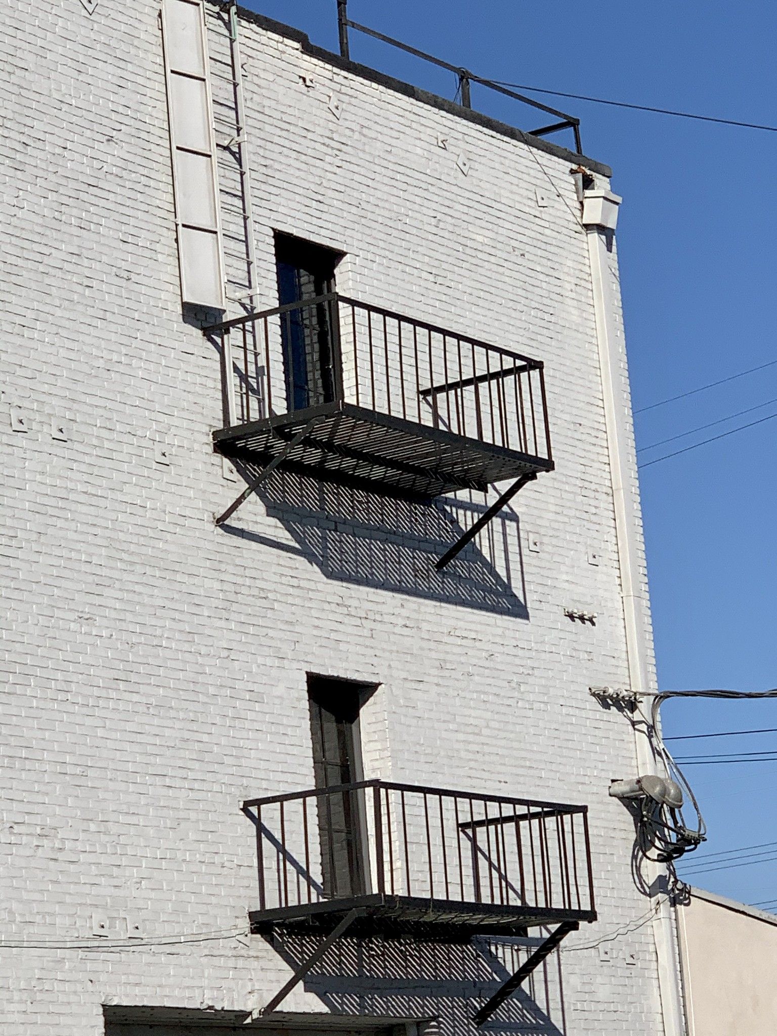 A white brick building with a fire escape on the side
