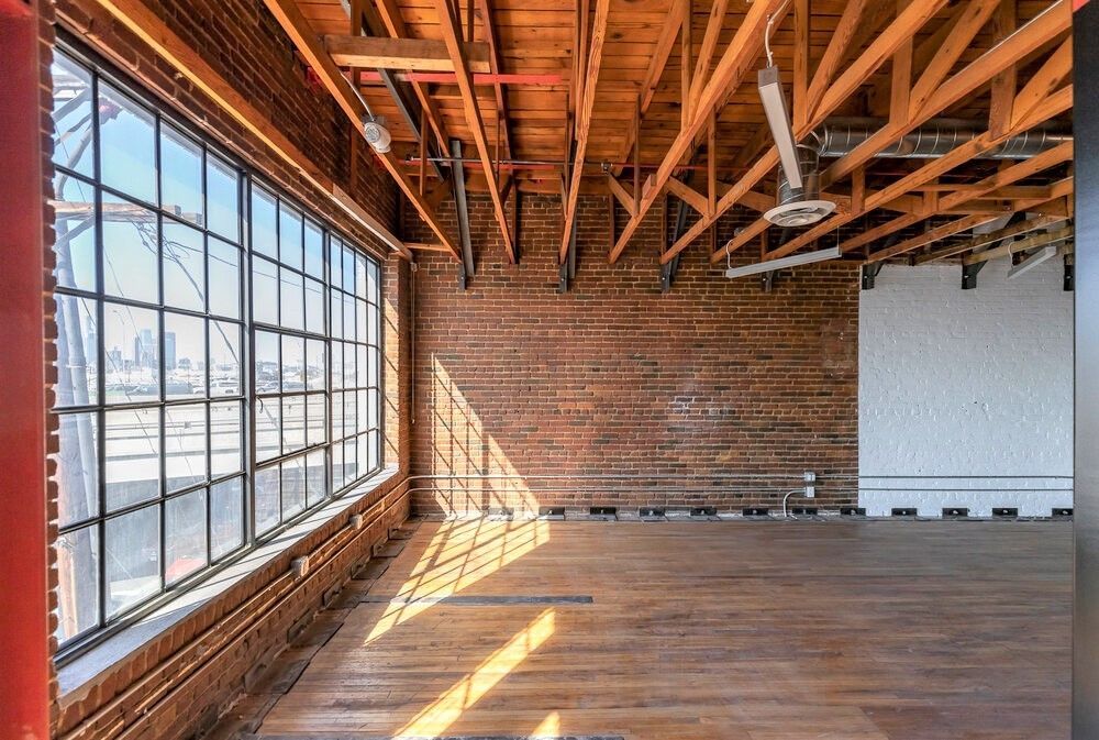 A large empty room with lots of windows and wooden beams.