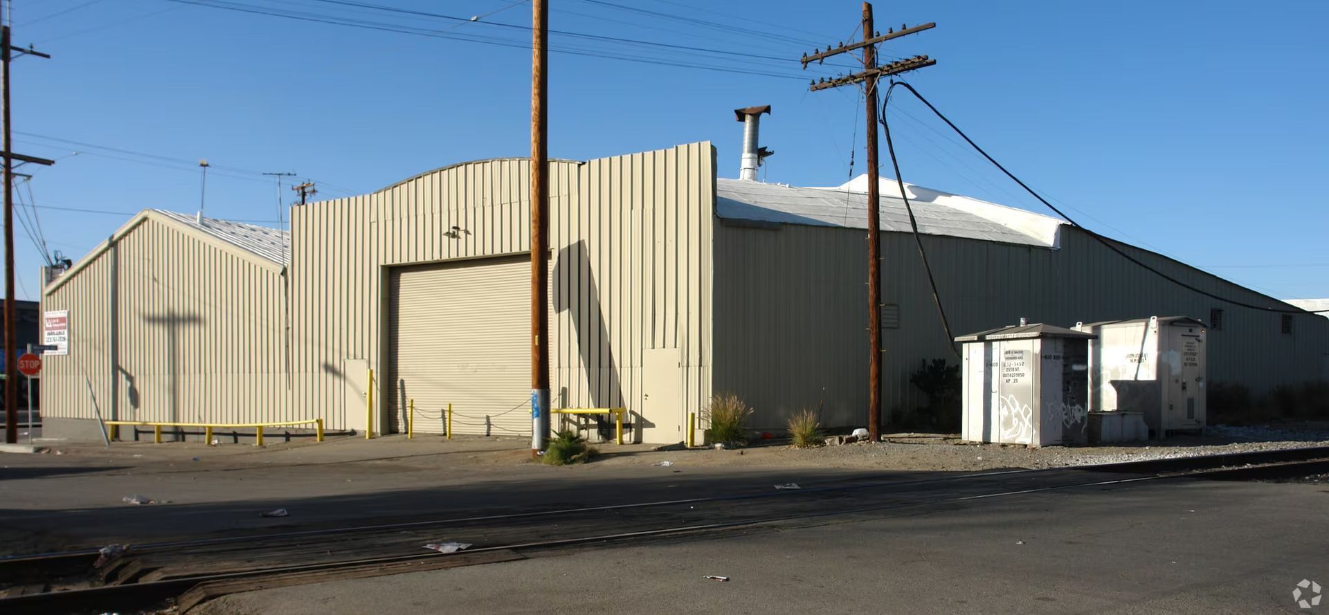 A large building with a large garage door is sitting on the side of the road.