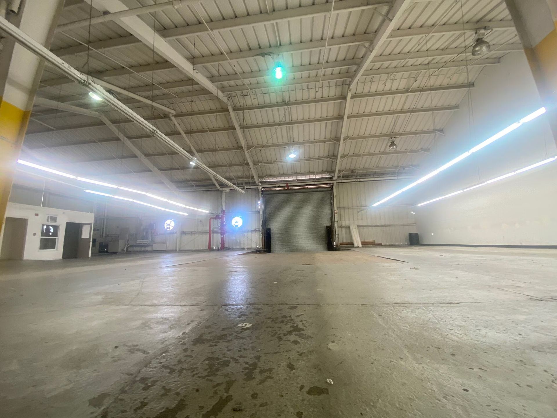 A large empty warehouse with a green light on the ceiling.