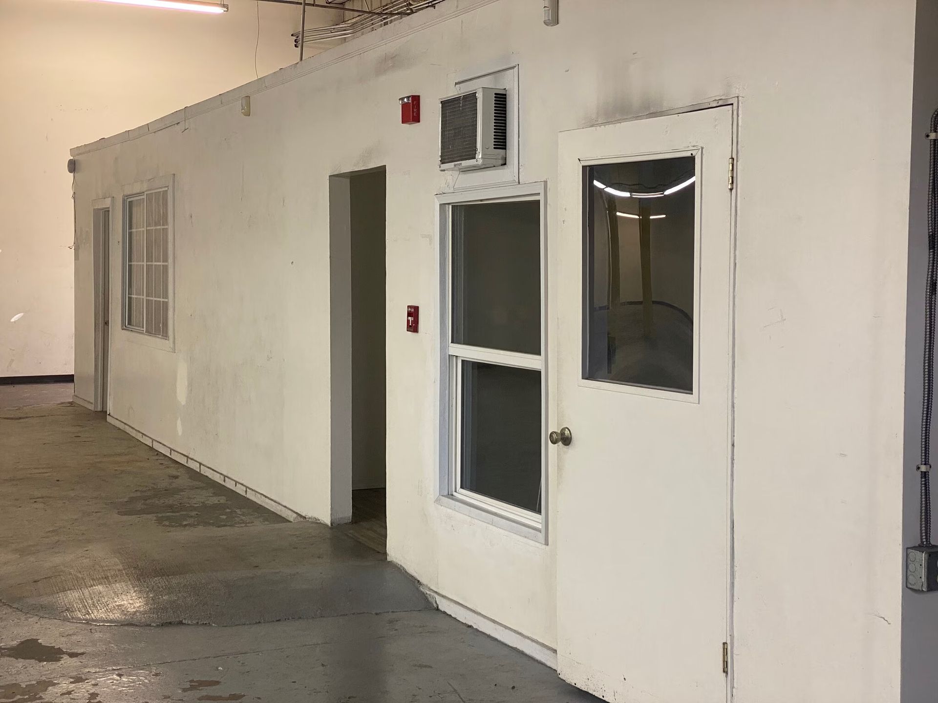 A white wall with a window and a door in a room.