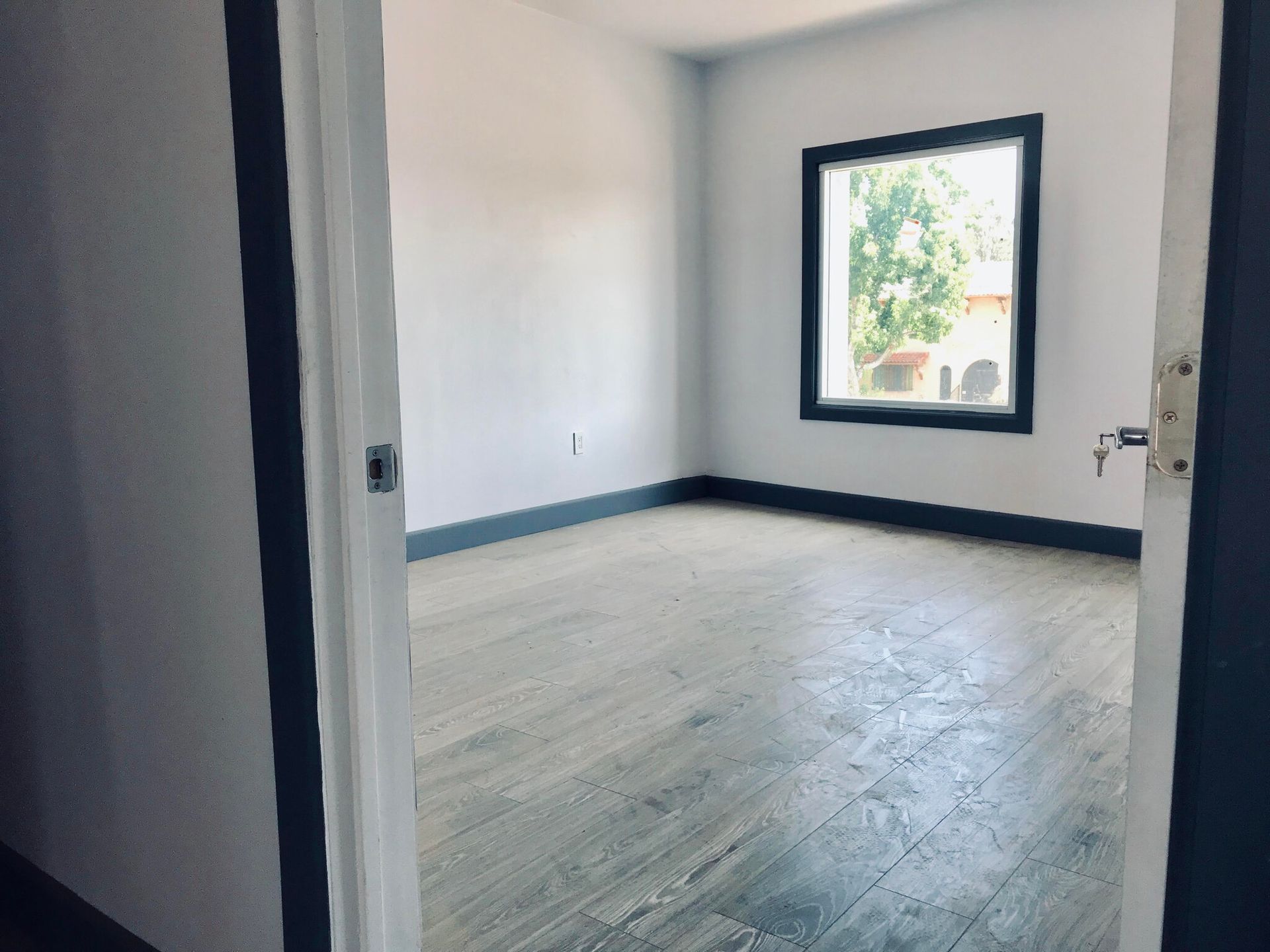 An empty room with a window and wooden floors