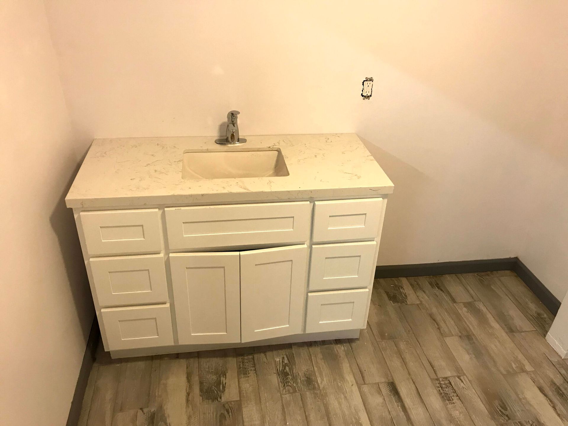 A bathroom vanity with a sink and drawers in a room.