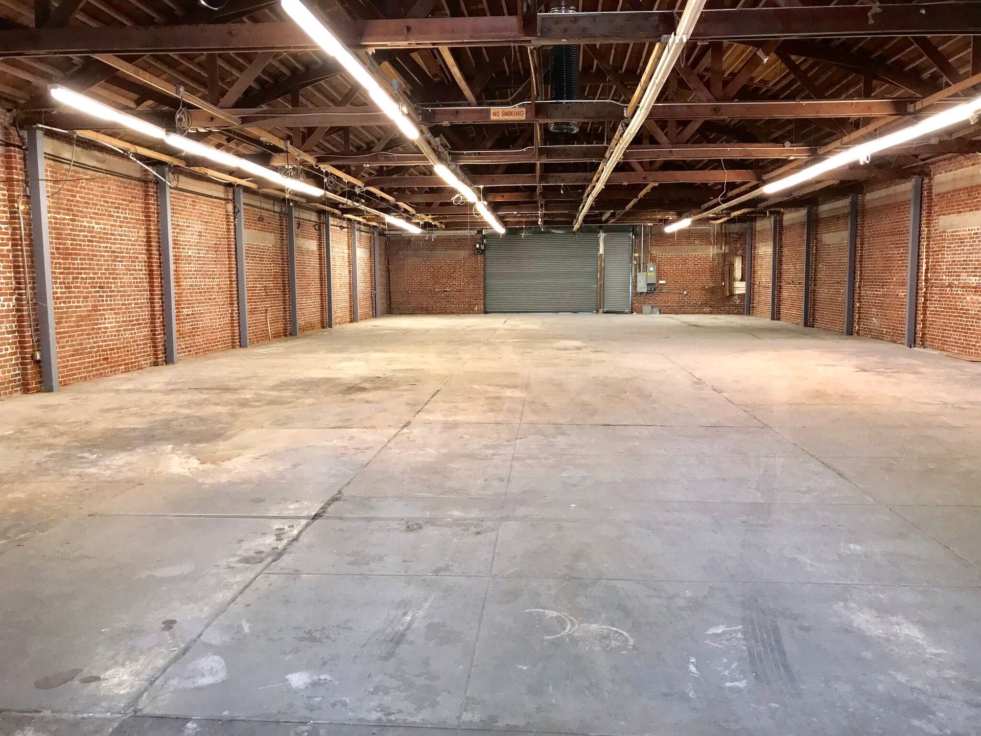 A large empty warehouse with brick walls and a garage door.