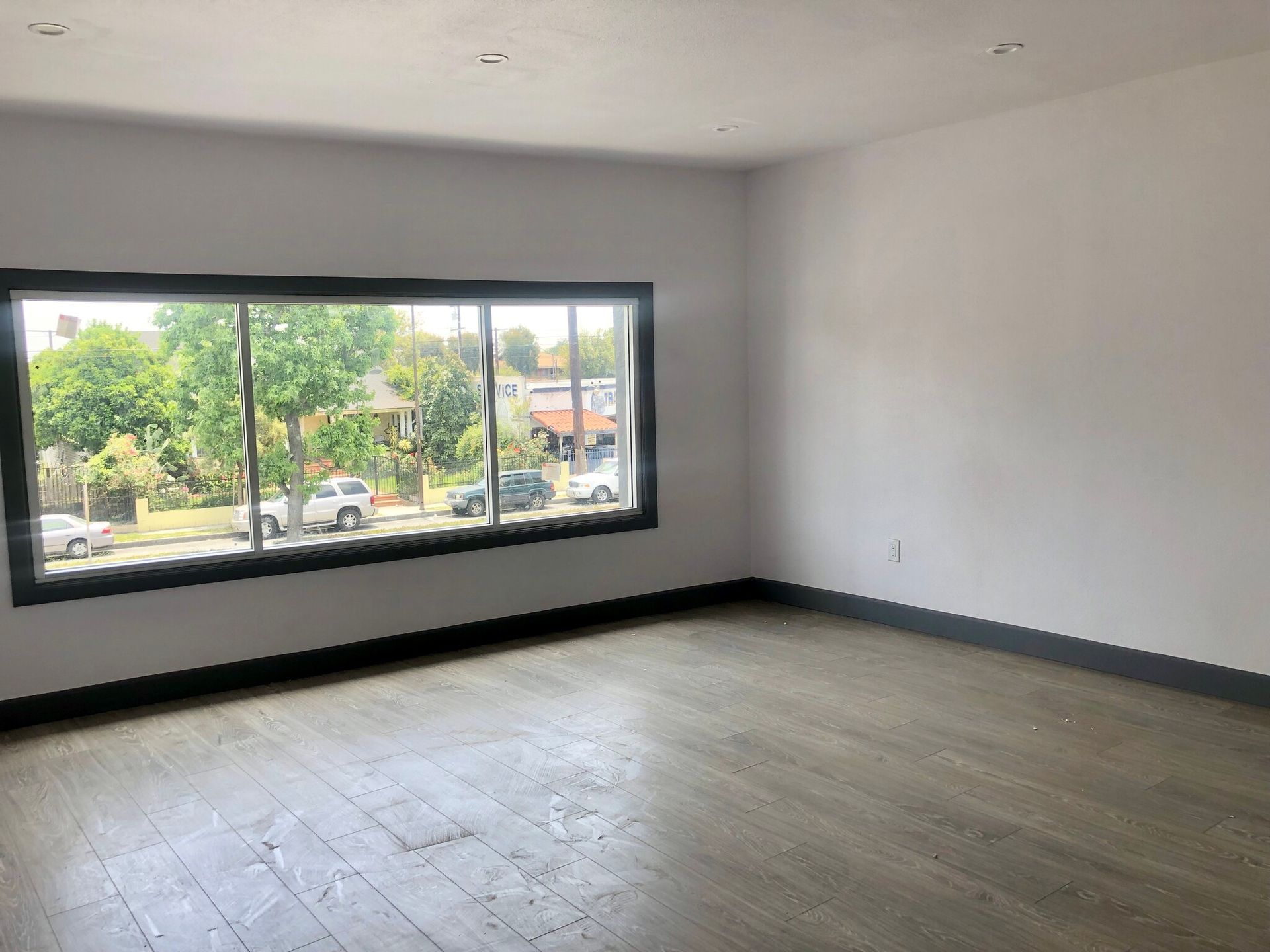 An empty room with a large window and a wooden floor.